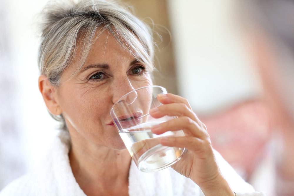 Close up of senior woman drinking glass of water