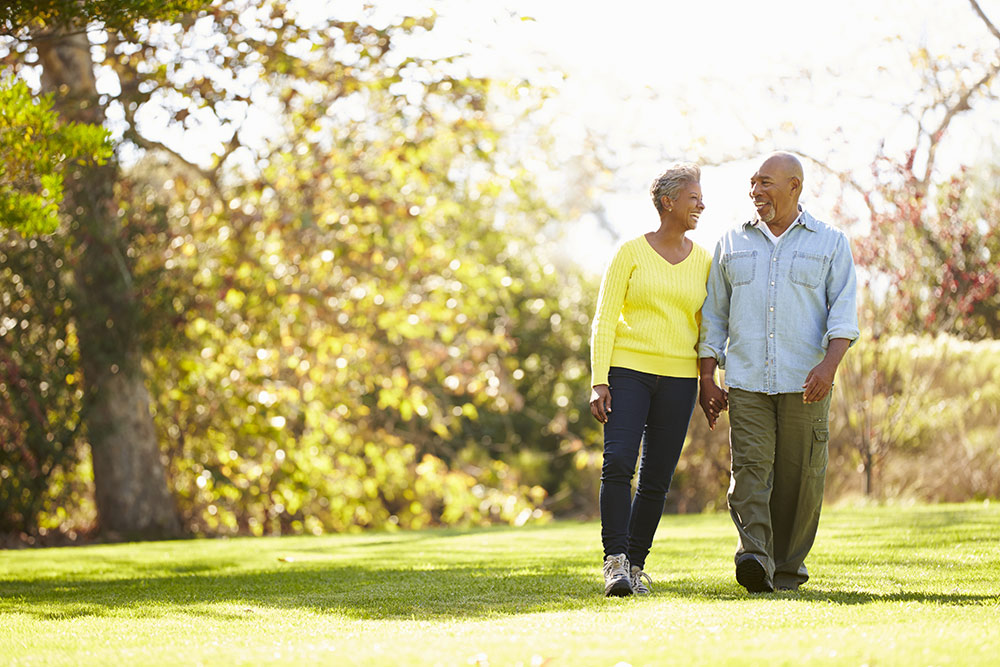 Senior man and woman walking outside in the grass around trees