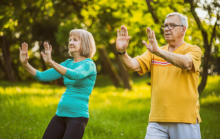 Senior man and woman outside practicing tai chi