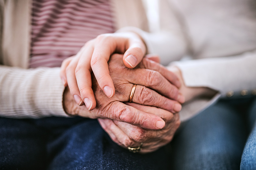 Caregiver holding senior hands, consoling, lost with dementia