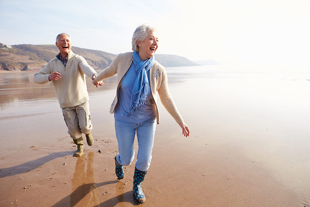 Happy senior couple walking on beach in Oceanside, CA