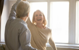 Happy senior couple smiling and dancing in living room