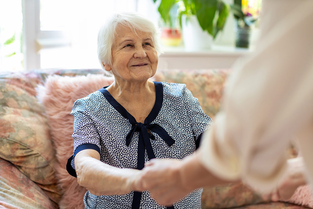 Senior woman getting assistance from caregiver in memory care community