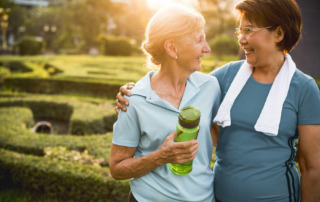 Two senior women outside smiling and working out