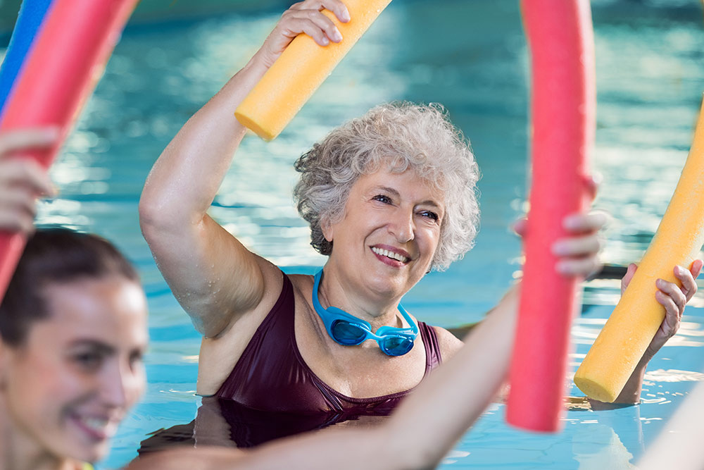Senior woman in water aerobics in pool in assisted living