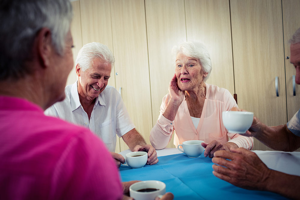 Senior friends sitting at table talking in independent living