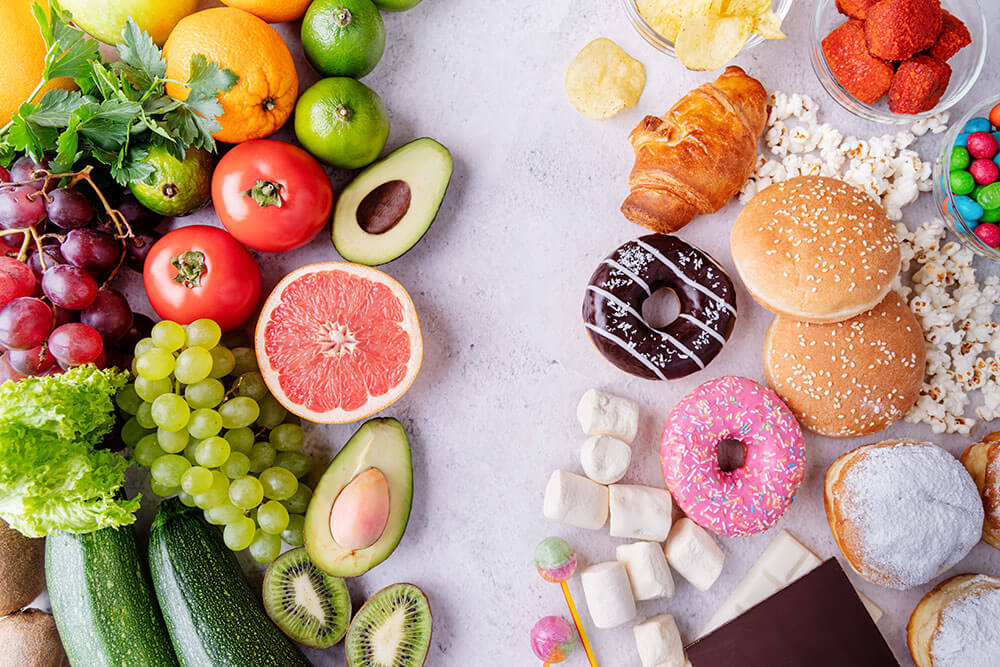 Healthy foods like fruits and vegetables on left side and unhealthy snacks like donuts and cookies on the right